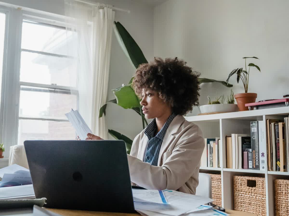 Professional woman working from a tidy home office desk with a laptop and paperwork.